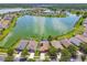 Aerial view of homes on a lake with lush lawns, a community park, and pools at 31244 Baclan Dr, Wesley Chapel, FL 33545