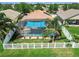 Aerial view of private backyard with screened in pool, palm trees, and white fence at 31244 Baclan Dr, Wesley Chapel, FL 33545