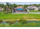 Aerial view of backyard with pool, palm trees, white fence, and waterfront view at 31244 Baclan Dr, Wesley Chapel, FL 33545