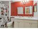 Bright bathroom with double sinks, tile flooring, a Mickey Mouse themed shower curtain, and a red accent wall at 31244 Baclan Dr, Wesley Chapel, FL 33545
