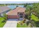 Aerial view of a well-maintained home with a brown roof, lush landscaping, and a lakeside backdrop at 31244 Baclan Dr, Wesley Chapel, FL 33545
