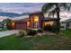 Evening view of single-story home featuring a well-maintained lawn and an attached two-car garage at 31244 Baclan Dr, Wesley Chapel, FL 33545