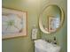 Stylish powder room with a round mirror, artwork, and modern fixtures set against a green wall at 325 5Th S Ave # 9, St Petersburg, FL 33701