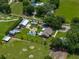 Aerial view of the estate showcasing a beautiful home, RV, multiple barns, pool, and lush greenery at 3412 Ace Ln, Dover, FL 33527