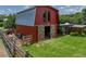 Quaint red barn with sliding doors, adjacent structures, and a fenced area on a well-manicured lawn at 3412 Ace Ln, Dover, FL 33527