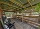 Covered barn area with rocking chairs overlooking livestock pens, blending comfort and functionality at 3412 Ace Ln, Dover, FL 33527