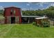 Charming red barn with sliding doors and adjacent shed, surrounded by lush greenery and a well-kept lawn at 3412 Ace Ln, Dover, FL 33527
