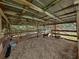 Spacious barn interior with hay, wooden beams, metal roof, and fenced pens, providing a secure shelter for livestock at 3412 Ace Ln, Dover, FL 33527