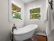 Bright bathroom featuring a freestanding tub, bronze faucet, and two windows at 3412 Ace Ln, Dover, FL 33527