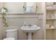 Bathroom featuring a pedestal sink, wainscotting, toilet, and shelves, combining classic design with functionality at 4206 W Palmira Ave, Tampa, FL 33629