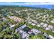 Aerial view of condo complex, pond with fountain, lush surrounding trees, and distant views of the bay at 500 New York Ave # 22, Dunedin, FL 34698