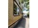 Side view of the brick home showing the driveway, windows, and mature trees providing shade at 535 22Nd N Ave, St Petersburg, FL 33704
