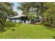 Exterior view of the back of the house showing yard with screen room, plants, palm tree, and trees at 5633 99Th N Ter, Pinellas Park, FL 33782