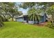 Exterior view of home shows the screen room, blue siding, lawn, and landscaped yard at 5633 99Th N Ter, Pinellas Park, FL 33782