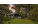 A beautiful sunset accentuates the screen room, plants, palm tree, and trees in this backyard exterior view at 5633 99Th N Ter, Pinellas Park, FL 33782