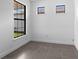 Minimalist bedroom features tiled flooring, baseboard trim, and a large window overlooking the yard at 6133 Wire Grass Ct, Nokomis, FL 34275
