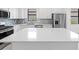 Bright kitchen with stainless steel appliances, white cabinets, mosaic backsplash, and a quartz island at 6133 Wire Grass Ct, Nokomis, FL 34275