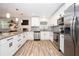 Well-lit kitchen with white cabinets, stainless steel appliances, and wood-look flooring at 615 6Th N Ave, Safety Harbor, FL 34695