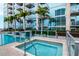 Relaxing hot tub next to pool area with lounge chairs, palm trees, and modern building backdrop at 777 N Ashley Dr # 2513, Tampa, FL 33602