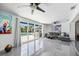 Stylish living room features gray tile, a modern ceiling fan, and sliding glass doors to the outdoor pool at 7892 10Th S Ave, St Petersburg, FL 33707