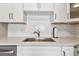 This kitchen features white subway tile, white cabinets, and a stainless steel sink at 8080 112Th St # 108, Seminole, FL 33772