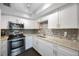 Bright kitchen with white cabinets, mosaic backsplash, granite counters, and stainless steel oven at 8100 Dr Martin Luther King Jr N St # 202, St Petersburg, FL 33702