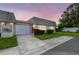 Charming home featuring a well-manicured lawn, red door, and attached garage at dusk at 8447 Orleans N, Pinellas Park, FL 33781