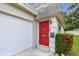 Close up of the front door, which is red, an attached garage, and manicured landscaping at 8447 Orleans N, Pinellas Park, FL 33781