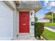 Vibrant red front door with elegant details, complemented by lush greenery and a well-maintained exterior at 8447 Orleans N, Pinellas Park, FL 33781