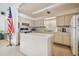 Kitchen featuring an island, neutral cabinets, essential appliances, and an American flag at 8447 Orleans N, Pinellas Park, FL 33781