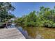 Private wooden dock on a canal surrounded by lush green foliage and serene water views at 8701 Driftwood Drive Dr, Tampa, FL 33615