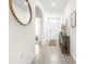 Bright hallway featuring tile flooring, neutral walls, an arched doorway, and stylish decorative mirror at 9098 Forge Breeze Loop, Wesley Chapel, FL 33545