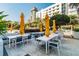 Outdoor dining space with modern tables, chairs, yellow umbrellas, and tropical landscaping at 100 1St N Ave # 2304, St Petersburg, FL 33701