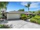 Front exterior featuring a well-manicured lawn, a two-car garage, and mature landscaping at 1000 Chatham Ct, Safety Harbor, FL 34695