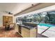 Outdoor kitchen with blue tile countertop, sink, and cooktop, overlooking a pool within a screened enclosure at 1000 Chatham Ct, Safety Harbor, FL 34695