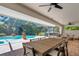 Covered patio area with outdoor dining, ceiling fans, and views of the pool and backyard at 1000 Chatham Ct, Safety Harbor, FL 34695