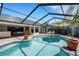 Inviting screened-in pool area with brick pavers, outdoor dining, a sunny umbrella, and lush tropical landscaping at 1000 Chatham Ct, Safety Harbor, FL 34695
