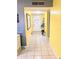 Inviting tiled hallway with a neutral color palette and bright yellow accent walls that guide you towards the front door at 10800 Us Highway 19 N # 143, Pinellas Park, FL 33782