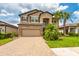 Inviting two-story home with a paver driveway, stone accents, and a well-manicured lawn at 11035 Sage Canyon Dr, Riverview, FL 33578