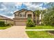 Charming two-story home featuring lush landscaping, a paver driveway, and a welcoming entrance at 11035 Sage Canyon Dr, Riverview, FL 33578