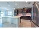 Modern kitchen featuring dark wood cabinetry, stainless steel appliances, a large island, and recessed lighting at 11035 Sage Canyon Dr, Riverview, FL 33578