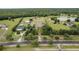 An aerial view of an estate with a pond, multiple buildings, mature trees, and white fences at 11430 Trotting Down Dr, Odessa, FL 33556