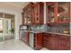 Butler's pantry featuring cherry cabinets with glass doors, granite countertops, wine refrigerator and sink at 11430 Trotting Down Dr, Odessa, FL 33556