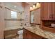 Elegant bathroom with a tiled tub, shower, granite countertop, and traditional wood vanity at 11430 Trotting Down Dr, Odessa, FL 33556
