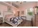 Cozy bedroom with light pink walls, wood floors, and a window overlooking the lush landscaping at 11430 Trotting Down Dr, Odessa, FL 33556