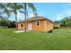 Rear exterior of cream colored home, green grass, palm trees and white fencing at 11430 Trotting Down Dr, Odessa, FL 33556