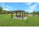 A gazebo with outdoor seating offers a relaxing view of the pond at 11430 Trotting Down Dr, Odessa, FL 33556
