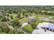 Estate aerial view showcasing a spacious home, with a green lawn, fenced paddock, and large outbuilding at 12637 Tyler Run Ave, Odessa, FL 33556