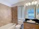 Well-lit bathroom with tile shower/tub combo, granite countertop, and window for natural light at 12637 Tyler Run Ave, Odessa, FL 33556