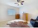 Relaxing bedroom with comfortable seating and two wooden dressers, illuminated by a unique ceiling fan at 12637 Tyler Run Ave, Odessa, FL 33556